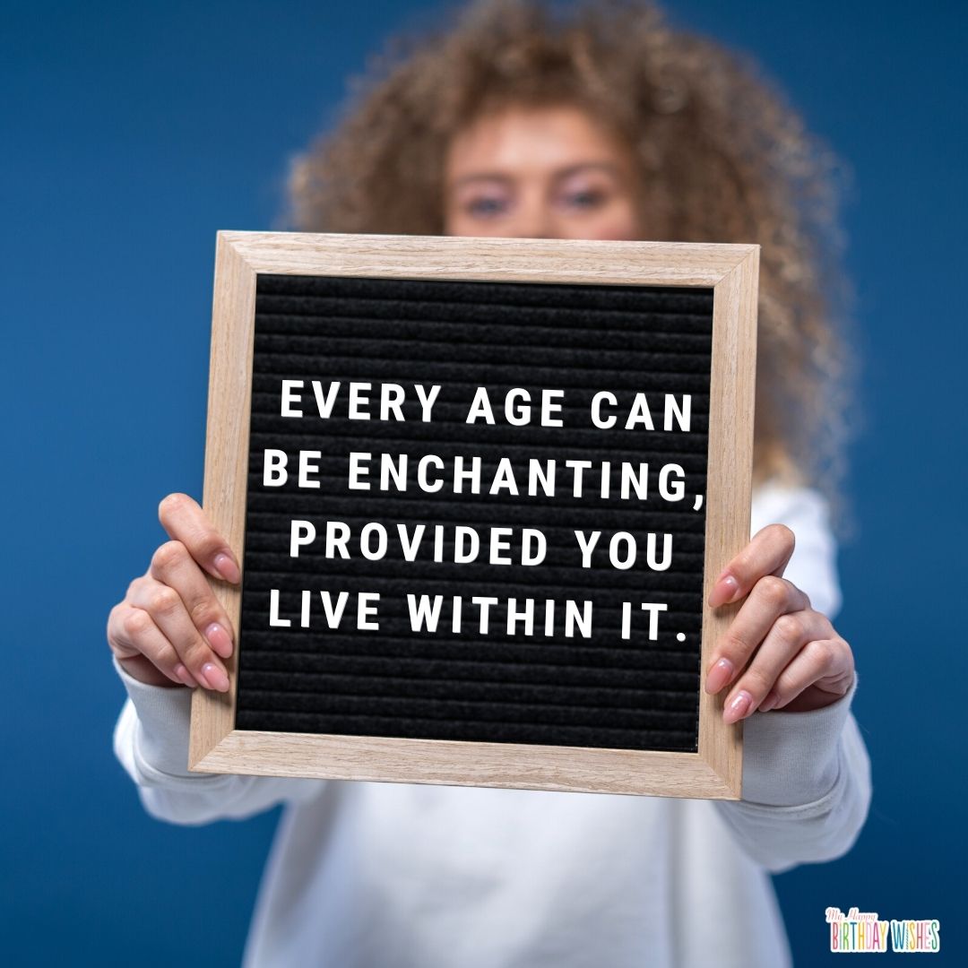 birthday quote about becoming enchanted on what you live within with person holding board in the background